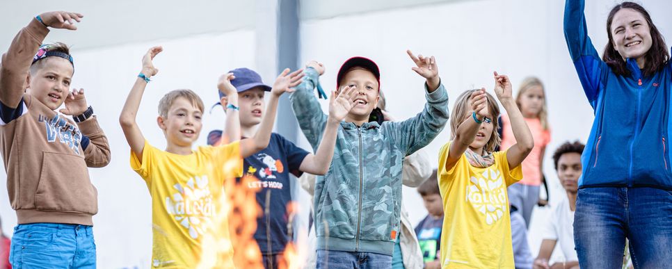 Mehrere Kinder bei einem Lagerfeuer.